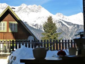 a house with a table in front of a snow covered mountain at Cozy mountain view apartment with terrace and garden in Innsbruck