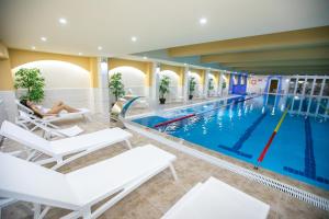 a swimming pool with a person sitting on a chair in front of it at AquaSun Family Hotel in Sandanski