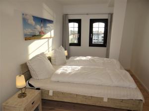 een bed met witte lakens en kussens in een slaapkamer bij Speicher Residenz Barth E4 App 10 in Barth