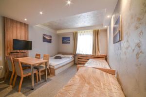 a room with two beds and a table with a desk at Apartments Suncani Vrhovi Kopaonik in Kopaonik