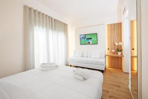 una camera bianca con un letto e un divano di Toscana Charme Resort a Tirrenia