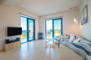 a living room with a couch and a tv at Villa Thalassa - Deja Vu Villas in Agios Nikolaos