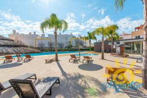 a patio with benches and a pool with palm trees at Cabanas Gardens by Algartur in Cabanas de Tavira