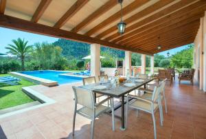 een patio met een tafel en stoelen en een zwembad bij Owl Booking Villa Romeu - 10 Min Walk to the Old Town in Pollença