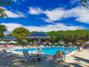 a swimming pool with people sitting in chairs and umbrellas at Salinello Village in Tortoreto Lido
