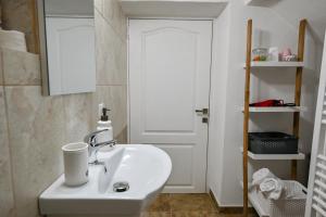 a bathroom with a sink and a white door at Transilvania Apartment in Sibiu