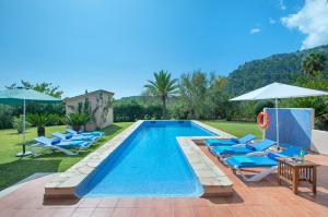 een zwembad met blauwe stoelen en parasols bij Owl Booking Villa Romeu - 10 Min Walk to the Old Town in Pollença