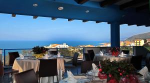 a restaurant with tables and chairs with a view of the ocean at Tus'Hotel in Castel di Tusa