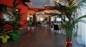 a restaurant with potted plants in a room with tables at Tus'Hotel in Castel di Tusa