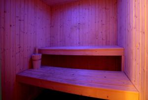 a wooden bench in a sauna with a pink wall at Tus'Hotel in Castel di Tusa