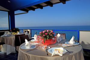 a dining room with two tables with flowers on them at Tus'Hotel in Castel di Tusa
