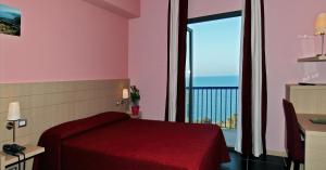 a bedroom with a red bed and a large window at Tus'Hotel in Castel di Tusa