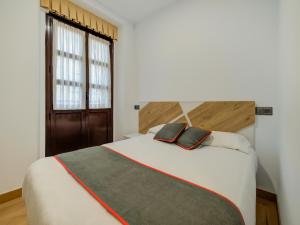 Un dormitorio con una gran cama blanca y una ventana en Hostal Restaurante La pinta, en Ampuero