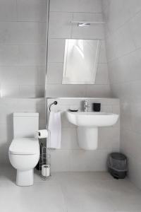 Baño blanco con aseo y lavamanos en Broadcroft Hotel, en Kirkintilloch