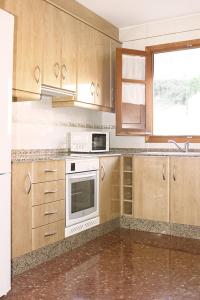 uma cozinha com armários de madeira e um forno de fogão branco em Vivienda Turística el Ciclamen em Mora de Rubielos