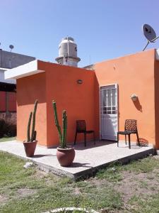 un edificio con dos sillas y dos cactus delante en Casa de Silvia en Villa Carlos Paz