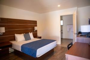 Schlafzimmer mit einem Bett, einem Schreibtisch und einem TV in der Unterkunft Sterling Inn in Santa Clara