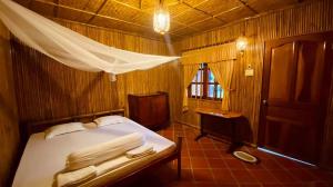 a bedroom with a bed and a table and a window at mekong riverside homestay in Vĩnh Long