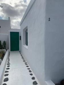 a white building with a green door and a sidewalk at Casa Callao in Famara