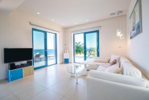 un soggiorno con divano bianco e TV di Villa Vrahos - Deja Vu Villas a Agios Nikolaos