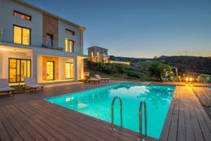 a villa with a swimming pool in front of a house at Villa Vrahos - Deja Vu Villas in Agios Nikolaos