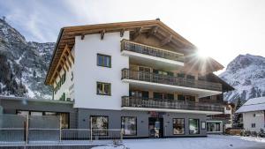 budynek w górach z śniegiem na ziemi w obiekcie Anthony´s Alpin Hotel Garni w Lech am Arlberg