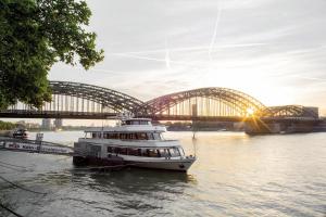 a white boat traveling down a river next to a bridge at Prevôt Restaurant & Hotel in Cologne
