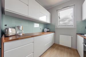 a kitchen with white cabinets and a window at Apartamenty Sun & Snow Spektrum in Gdańsk