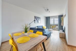 a living room with a table and a blue couch at Apartamenty Sun & Snow Spektrum in Gdańsk