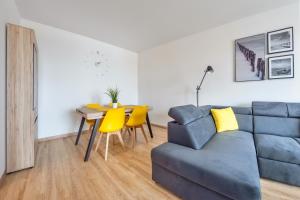 a living room with a couch and a table and yellow chairs at Apartamenty Sun & Snow Spektrum in Gdańsk