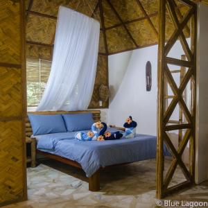 two people sitting on a bed in a room at Blue Lagoon Dive Resort in Sabang