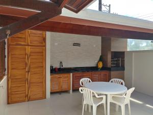 a kitchen with a white table and white chairs at Casa Praia de Maresias in Maresias