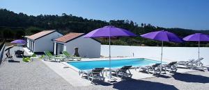 una piscina con sillas y sombrillas púrpuras en VillaVie CostadePrata, en Alfeizerão