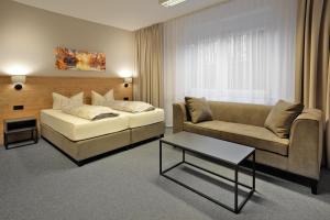 a living room with a bed and a couch and a table at BELLEVUE-Boardinghouse in Lichtenfels