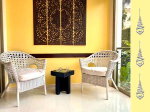 dwa krzesła i stół przed żółtą ścianą w obiekcie Apt S104 Kamala Regent w mieście Kamala Beach