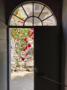 une porte menant à une fenêtre ornée de fleurs rouges dans l'établissement Ca Spontoi Do-Minus guesthouse & Mini Spa, à Gnosca