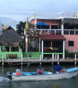 dos personas en un barco en el agua cerca de una casa en Villa Santa Barbara, en Barra de Navidad