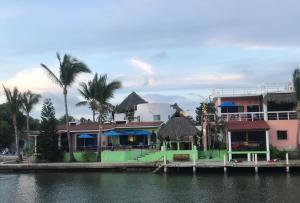 una casa verde al lado de un cuerpo de agua en Villa Santa Barbara, en Barra de Navidad