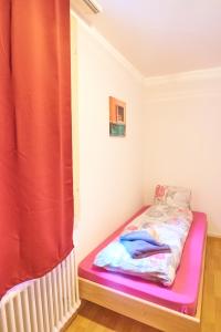 a small bed in a room with a red curtain at Golden River in Unterseen
