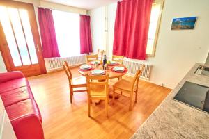 a dining room with a table and chairs and red curtains at Golden River in Unterseen