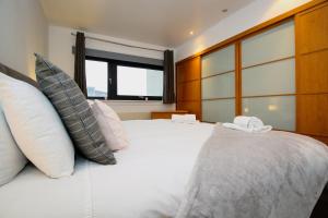 een slaapkamer met een groot wit bed met kussens bij Hydro Apartments in Glasgow