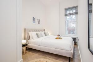 a white bedroom with a bed and a window at Kula London - Fitzrovia Newman St in London