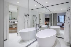 a white bathroom with three sinks and mirrors at The Level at Melia White House in London