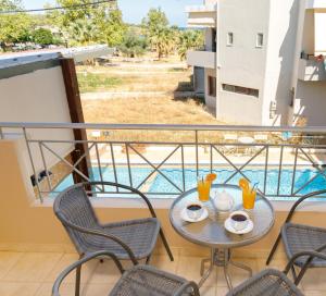 balcón con mesa, sillas y piscina en Sun Beach Apartments, en Kato Daratso