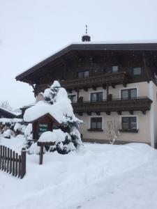 una casa cubierta de nieve con un árbol cubierto de nieve en Landhof Aigner, en Mittersill