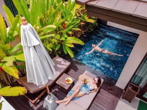 a woman sitting in a chair next to a swimming pool at Khanom Beach Resort And Spa in Khanom