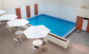 a swimming pool with tables and white umbrellas at Hotel Suite Luna del Valle in Jaén