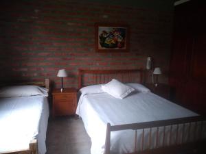 a bedroom with two beds and a brick wall at El Indalo La Calderilla in Salta