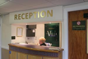 a woman sitting at a reception desk in a waiting room at The Villa Express in Kirkham