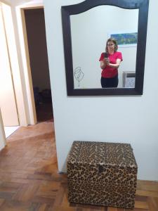 Eine Frau, die vor einem Spiegel mit einer Kiste steht. in der Unterkunft Casa Livramento Rivera diária in Santana do Livramento